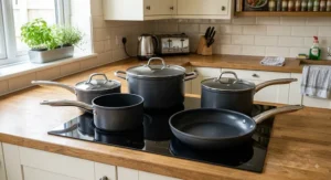 Non-stick 5-piece pan set under £100 arranged on an induction hob showing stainless steel pan handles